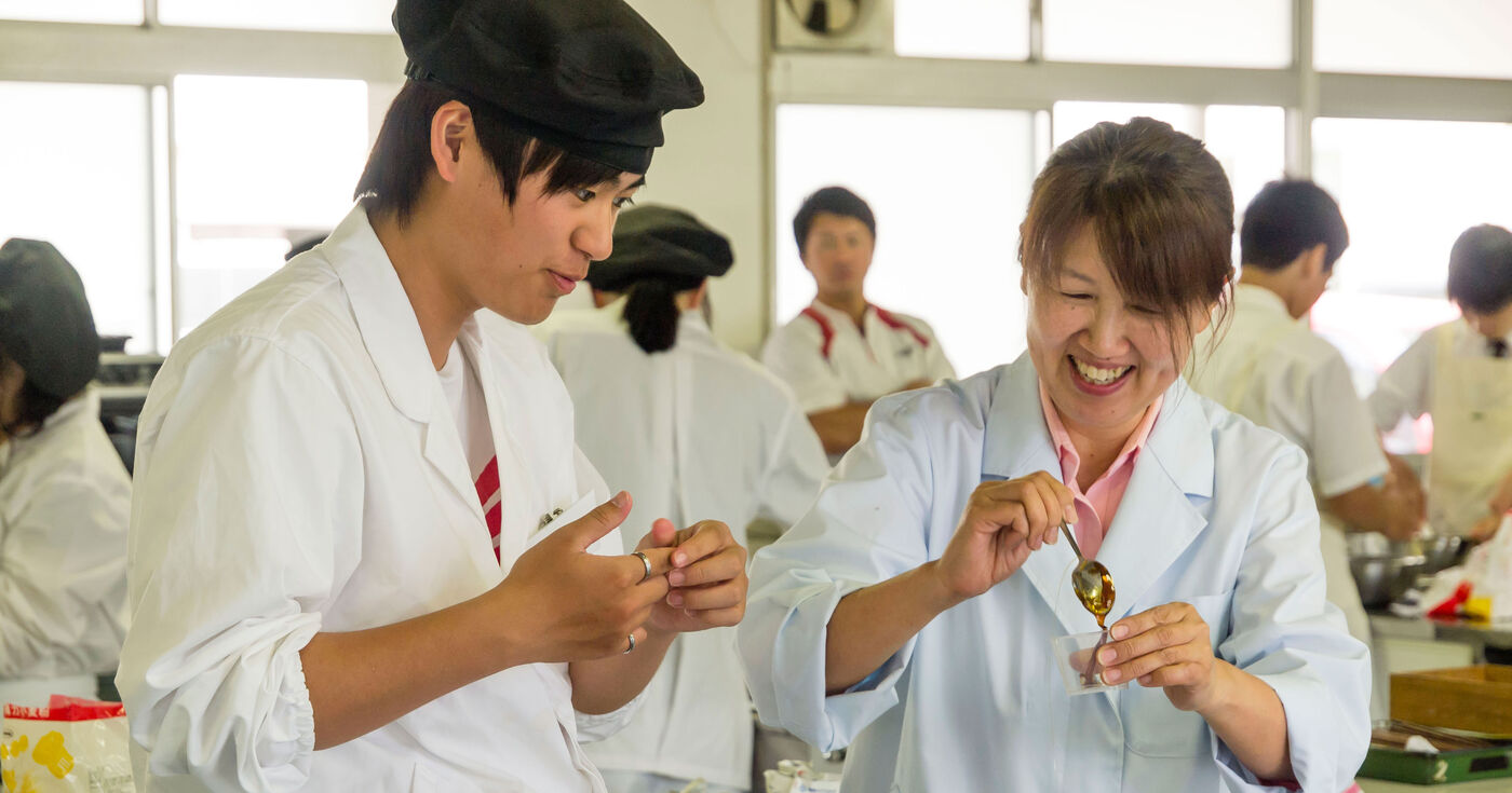 学校での料理教室で、生徒さんと笑う講師
